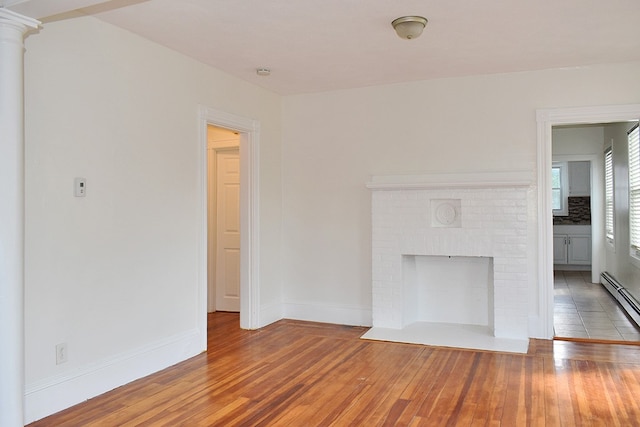 unfurnished living room with a brick fireplace, baseboards, and hardwood / wood-style floors