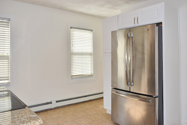 kitchen featuring a baseboard heating unit, freestanding refrigerator, white cabinets, and light stone counters