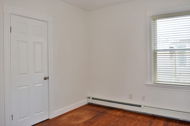 spare room with a baseboard heating unit, dark wood-type flooring, and a wealth of natural light