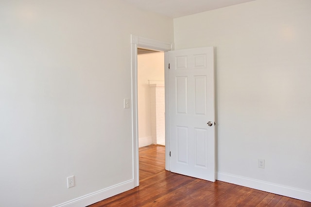 spare room featuring dark wood-style flooring and baseboards