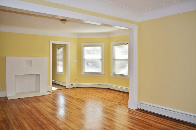 unfurnished living room featuring a baseboard radiator, a brick fireplace, and wood finished floors