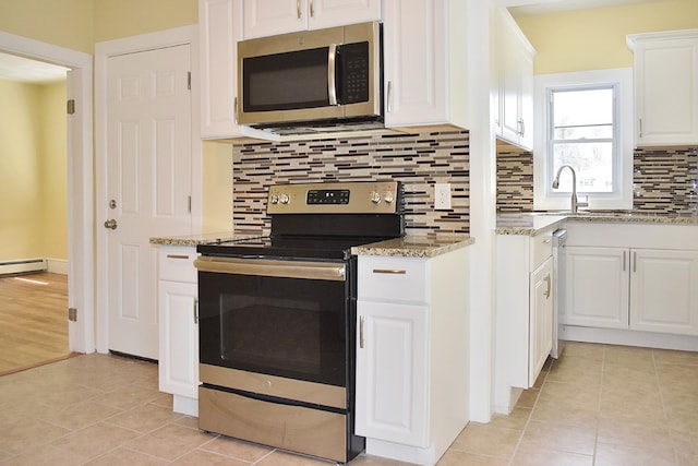 kitchen featuring light stone counters, stainless steel appliances, tasteful backsplash, white cabinets, and a sink