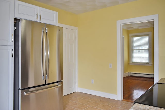 kitchen featuring a baseboard radiator, freestanding refrigerator, white cabinets, range, and baseboards