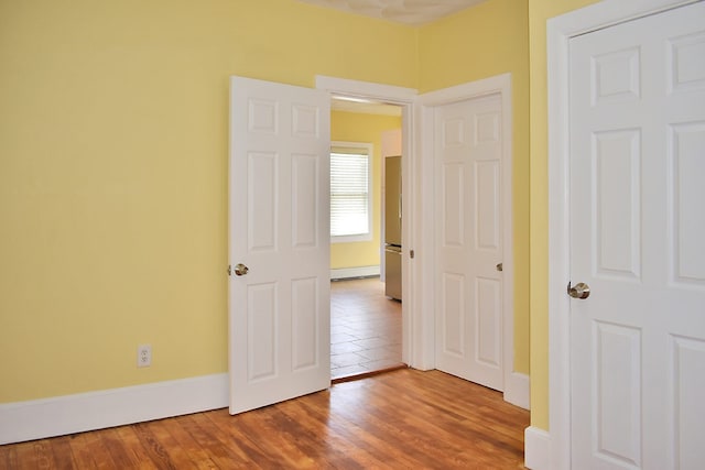 interior space with baseboard heating, wood finished floors, and baseboards