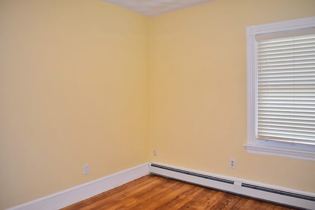 unfurnished room with a baseboard radiator, wood finished floors, and baseboards