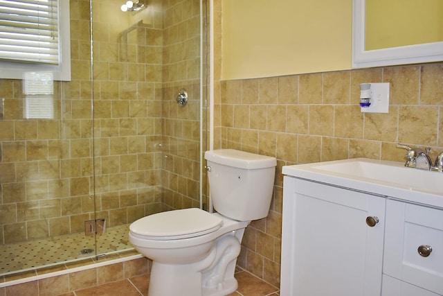 bathroom with toilet, vanity, tile walls, wainscoting, and a stall shower