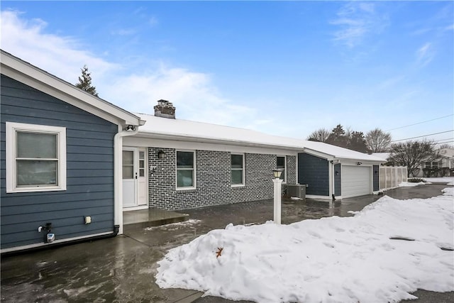 view of front facade featuring an attached garage, a chimney, and central AC unit