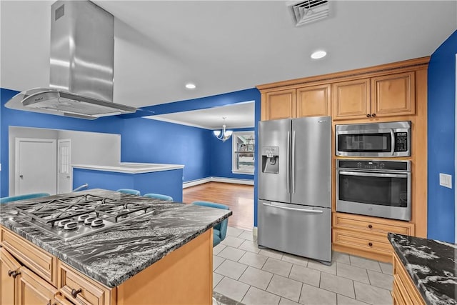 kitchen featuring a center island, stainless steel appliances, visible vents, island range hood, and dark stone countertops