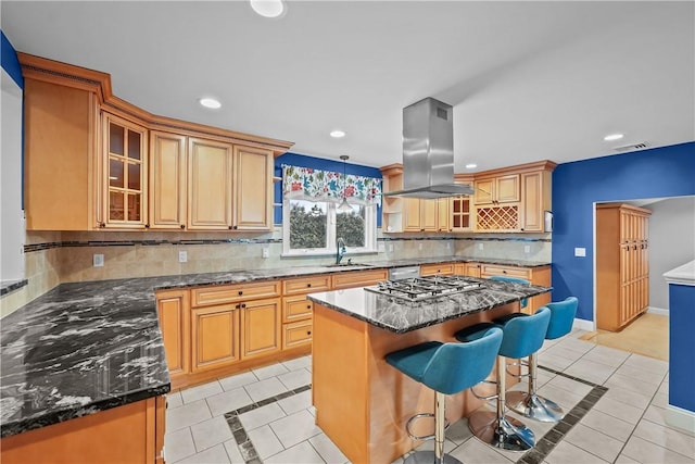 kitchen with glass insert cabinets, a kitchen island, hanging light fixtures, and island range hood