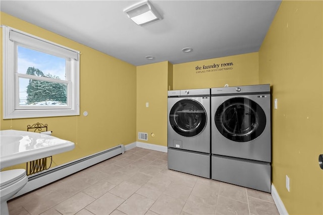 washroom with a baseboard heating unit, light tile patterned floors, baseboards, and separate washer and dryer