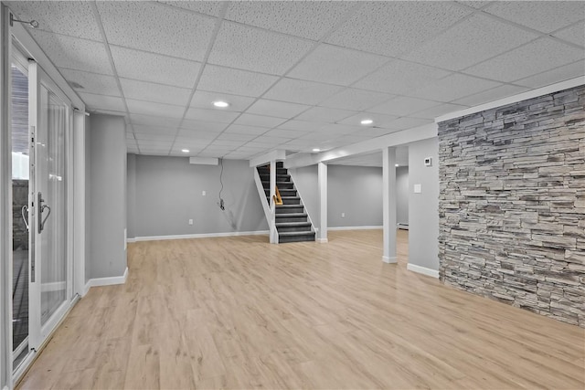 finished basement featuring recessed lighting, stairway, light wood-type flooring, a drop ceiling, and baseboards