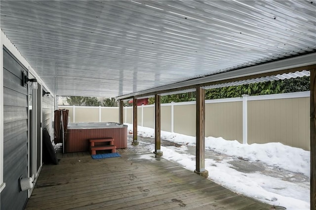 snow covered deck with a hot tub and a fenced backyard