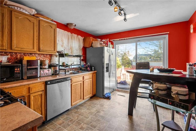 kitchen with a sink, visible vents, light countertops, appliances with stainless steel finishes, and brown cabinetry