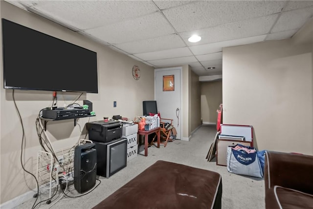 recreation room featuring light carpet, a drop ceiling, and baseboards