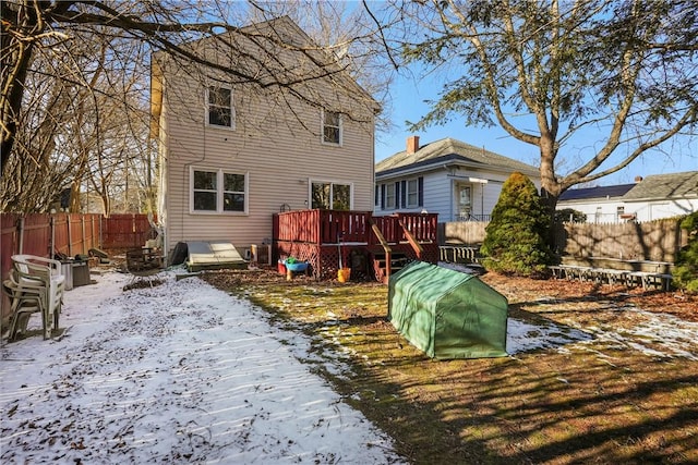 snow covered rear of property with fence and a wooden deck