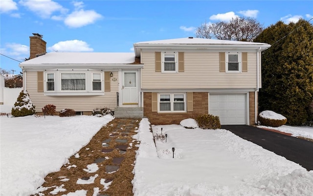 tri-level home with a garage, driveway, and a chimney