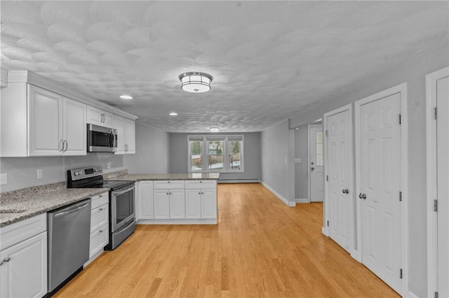 kitchen with baseboards, appliances with stainless steel finishes, a peninsula, light wood-type flooring, and white cabinetry