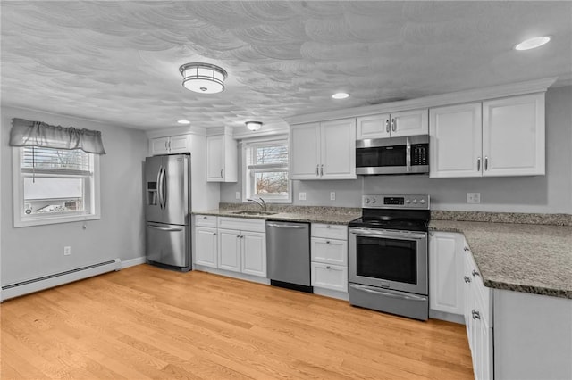 kitchen featuring a baseboard radiator, appliances with stainless steel finishes, and white cabinets