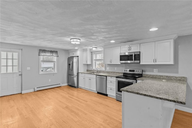 kitchen featuring a baseboard radiator, light wood-style flooring, a peninsula, white cabinets, and appliances with stainless steel finishes