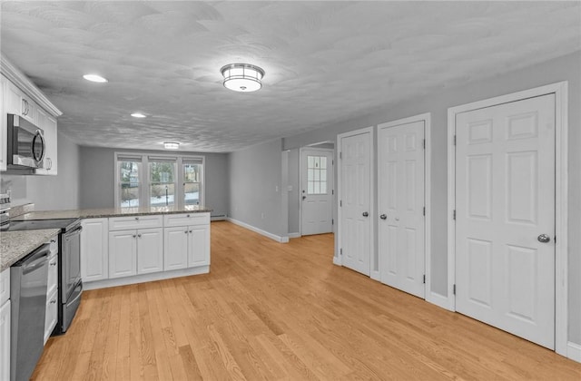 kitchen featuring a peninsula, light wood-style flooring, appliances with stainless steel finishes, and white cabinets