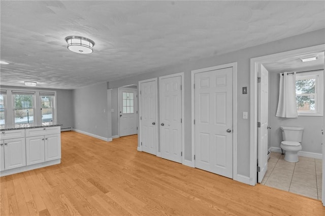 interior space featuring baseboards, a baseboard radiator, and light wood-style floors