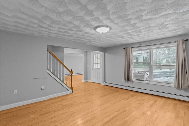 unfurnished room featuring baseboards, a baseboard radiator, stairway, a textured ceiling, and light wood-type flooring