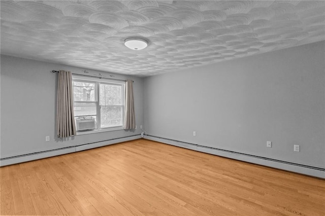 unfurnished room with light wood-style floors, a baseboard heating unit, and a textured ceiling