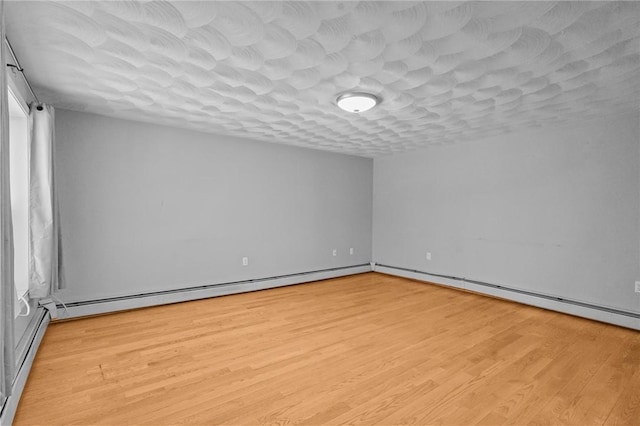 spare room featuring a textured ceiling, light wood finished floors, and a baseboard radiator