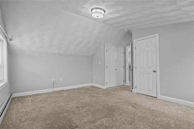 additional living space featuring a baseboard heating unit, carpet, lofted ceiling, and baseboards