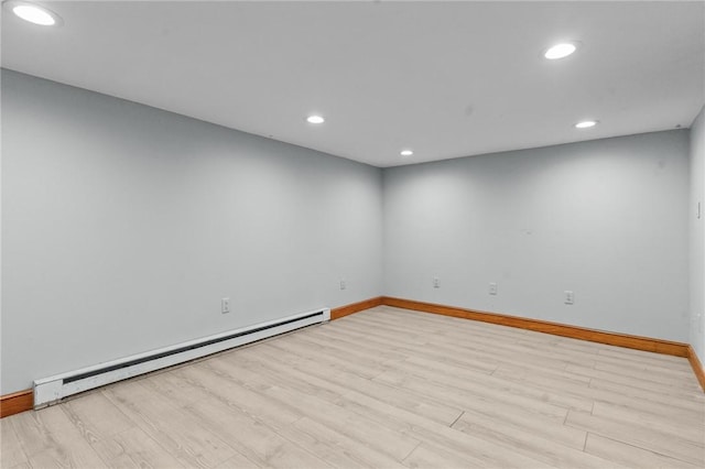 empty room with a baseboard radiator, light wood-style flooring, baseboards, and recessed lighting