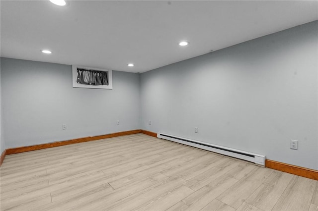 finished below grade area with light wood-style floors, baseboards, baseboard heating, and recessed lighting