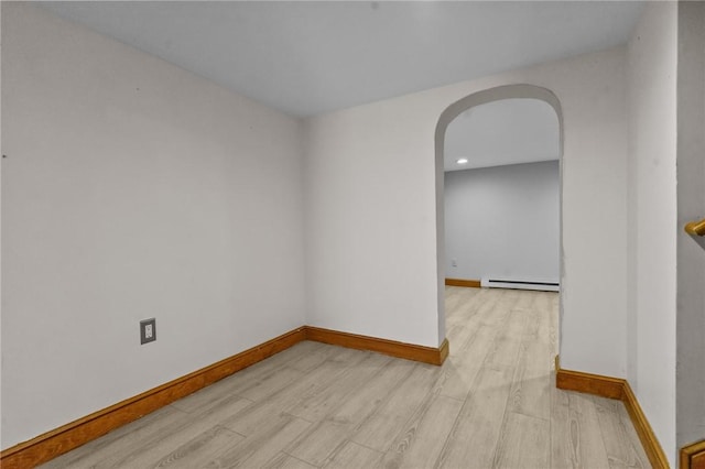 unfurnished room with a baseboard heating unit, light wood-style flooring, arched walkways, and baseboards