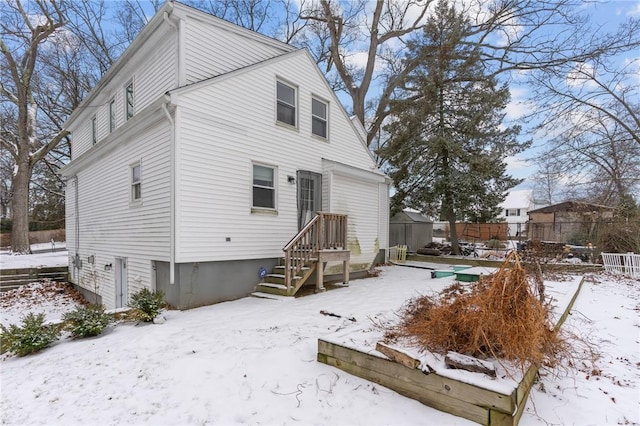 snow covered rear of property with fence