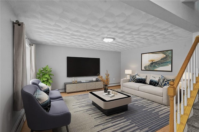 living room with a baseboard radiator, wood finished floors, a textured ceiling, and stairs