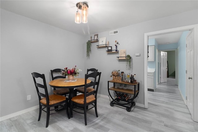 dining room with light wood-style floors, baseboards, and visible vents