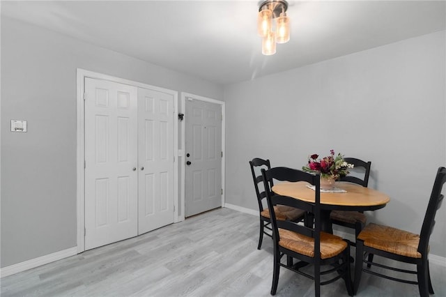 dining space featuring light wood-style flooring and baseboards