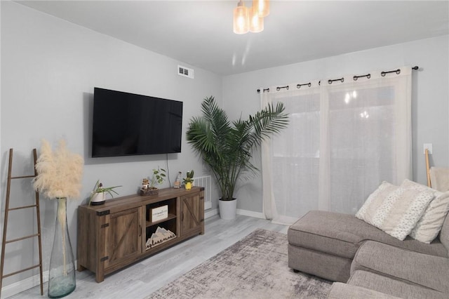 living area with baseboards, visible vents, and wood finished floors