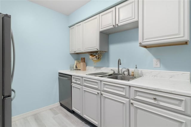 kitchen featuring appliances with stainless steel finishes, light countertops, a sink, and baseboards