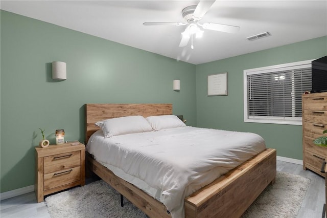 bedroom featuring visible vents, ceiling fan, baseboards, and wood finished floors