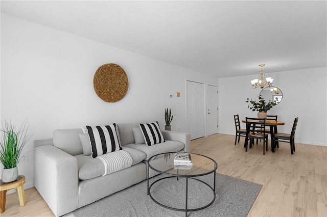 living room featuring light wood-style floors, a chandelier, and baseboards