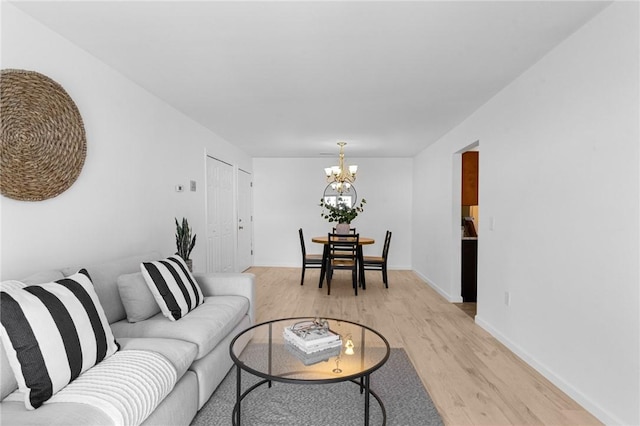 living area featuring light wood-type flooring, an inviting chandelier, and baseboards