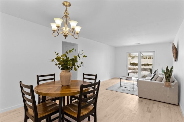 dining space with a chandelier, baseboards, and light wood finished floors