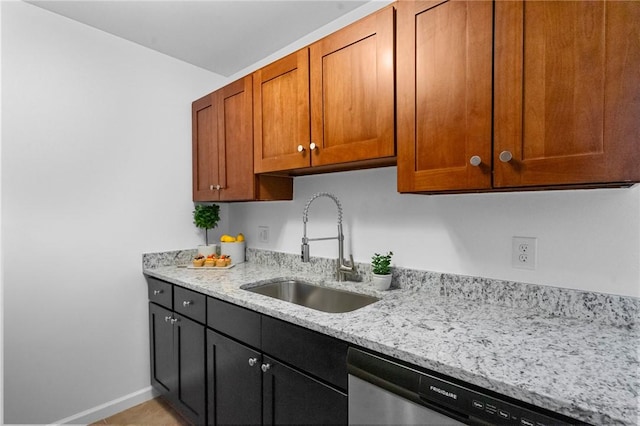 kitchen with brown cabinets, a sink, light stone countertops, dishwasher, and baseboards