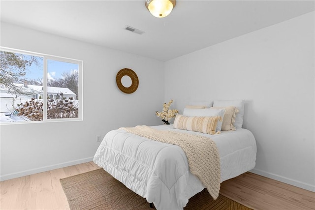 bedroom with visible vents, baseboards, and wood finished floors