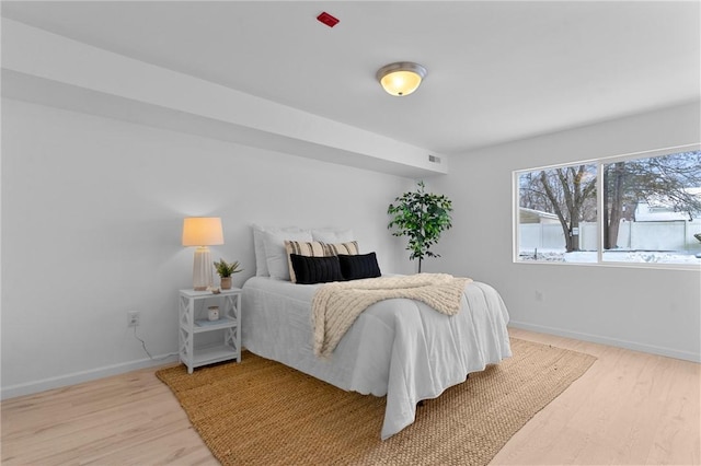 bedroom featuring visible vents, baseboards, and wood finished floors