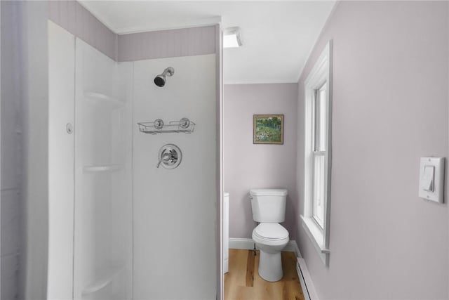 bathroom featuring baseboards, walk in shower, toilet, and wood finished floors