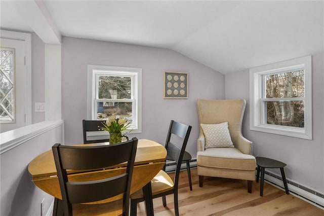 dining room with lofted ceiling, baseboard heating, and light wood-style floors