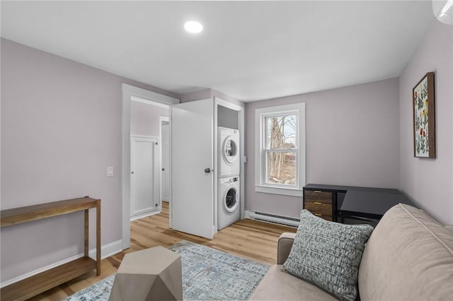 sitting room with stacked washer and dryer, light wood-style flooring, a baseboard heating unit, and baseboards