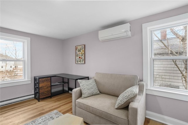 sitting room featuring an AC wall unit, light wood-type flooring, a baseboard radiator, and baseboards