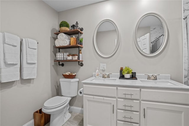 full bath featuring toilet, double vanity, baseboards, and a sink